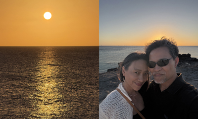 Golden sun setting over a calm ocean horizon, casting a shimmering reflection on the water surface, and a couple posing closely together at sunset on Ocean Cay, with the sun low on the horizon behind them, creating a warm, romantic glow.
